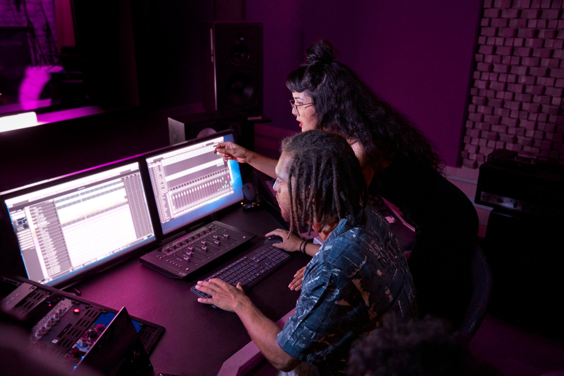 Mixed-race female artist working with african-american music producer on her song in music studio